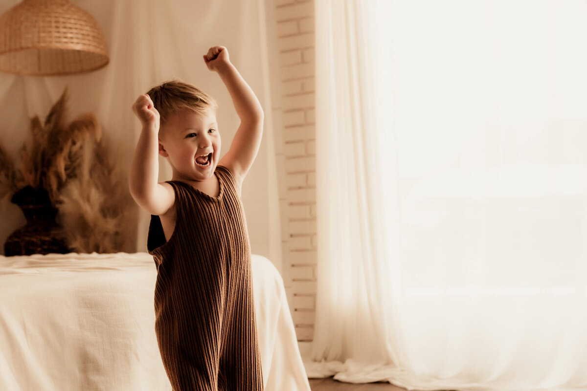 Boy excitedly smiling with his arms in the air.