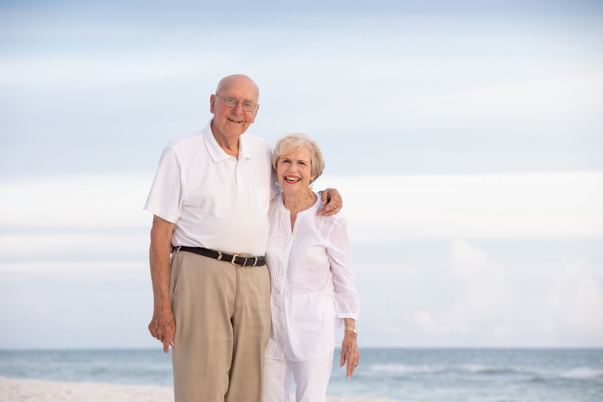 An older couple smiling at the beach