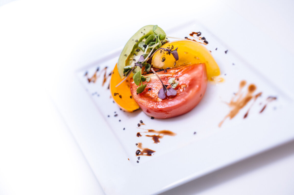 Colorful heirloom tomato salad with microgreens, avocado, and balsamic drizzle, artfully plated at The Seclusion wedding venue in Virginia.