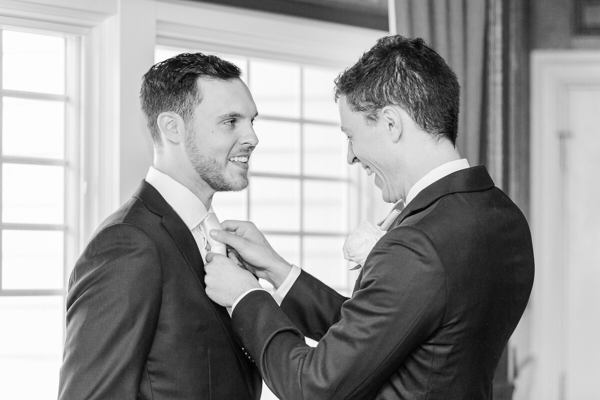 Best man adjusts the groom's tie before his Madison Beach Hotel wedding. Captured by best New England wedding photographer Lia Rose Weddings.
