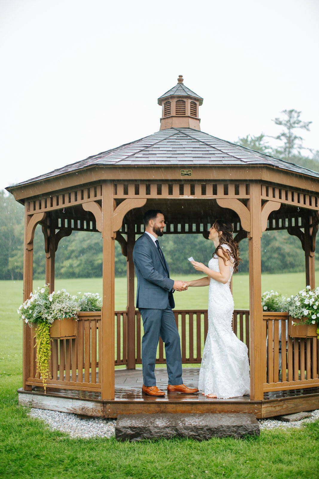 bride and groom reading vows to each other in gazebo at rainy mountain top inn and resort wedding in vermont