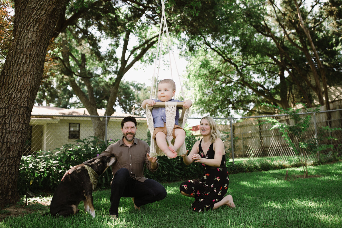 Child in swing with mother and father looking on