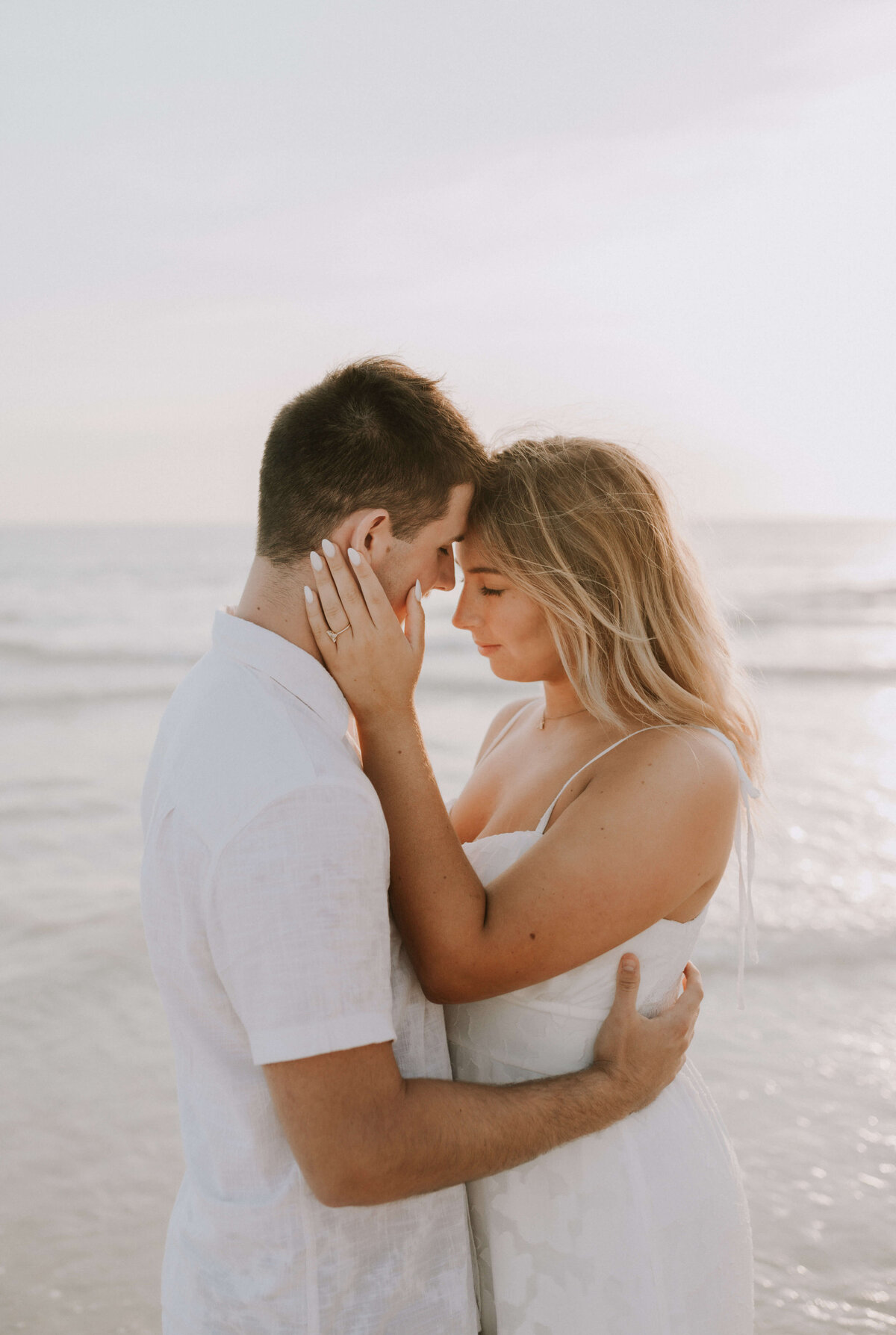 newly engaged couple snuggle together on beach in PCB, taken by Panama City wedding photographer Brittney Stanley
