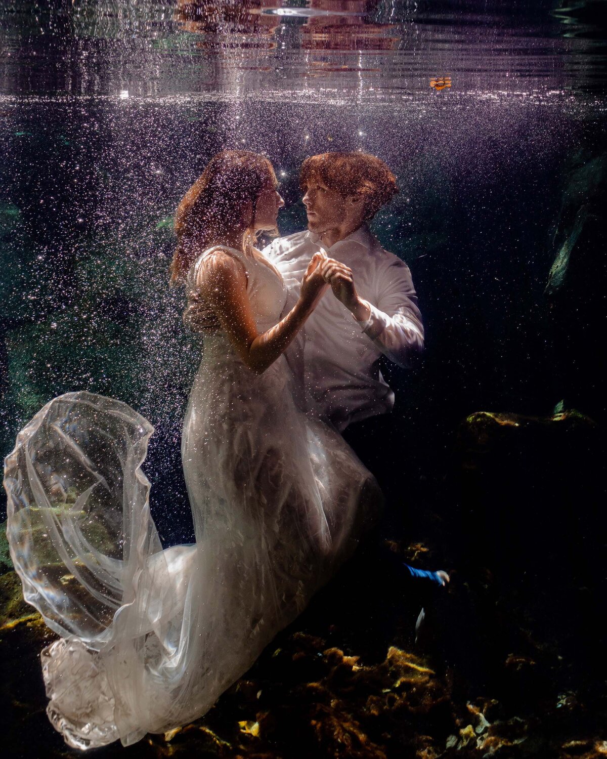 Groom holding bride underwater during TTD in Riviera Maya