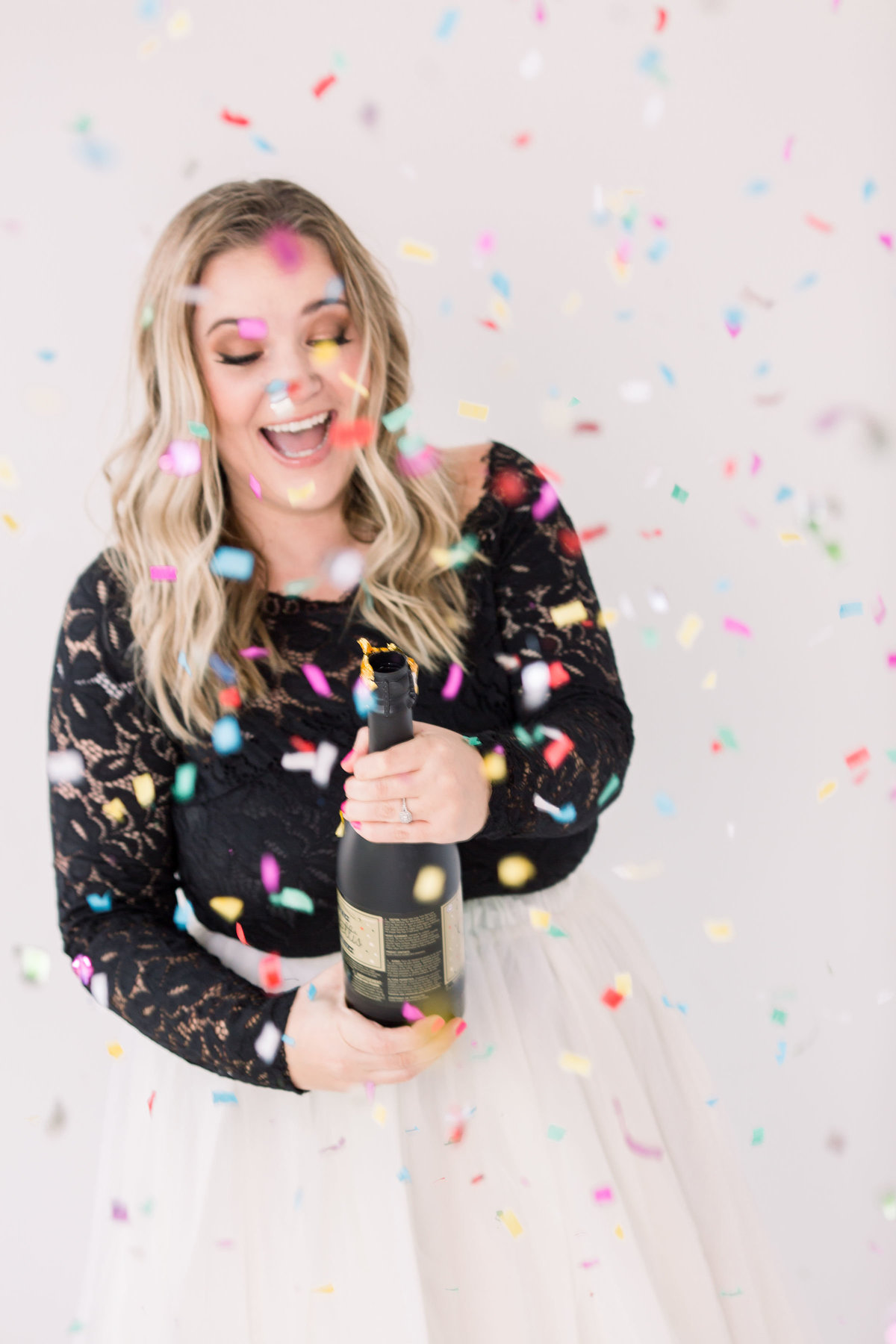 Woman popping bottle of champagne with confetti