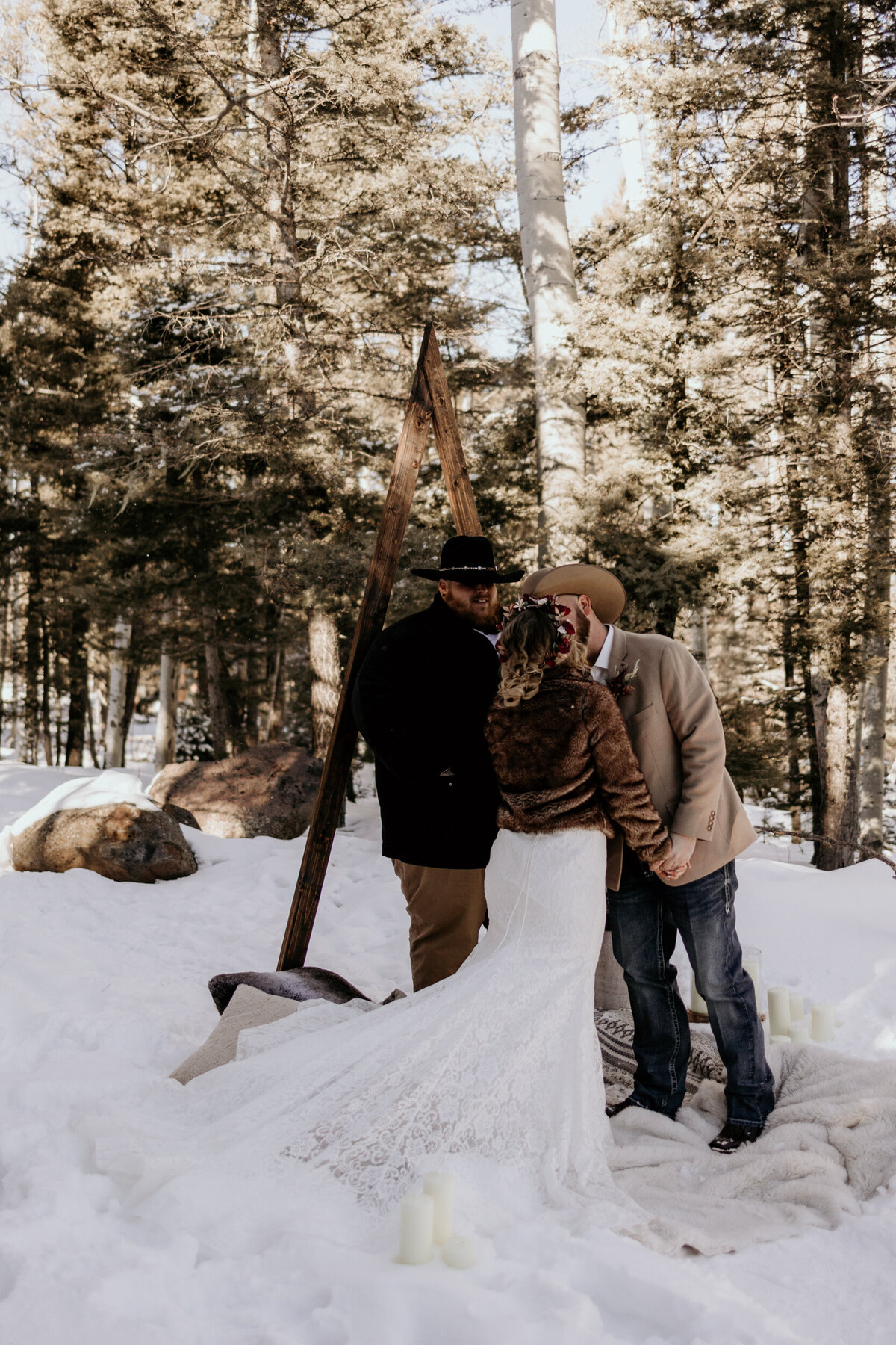 bride and grooms first kiss in the snow in Angel Fire New Mexico