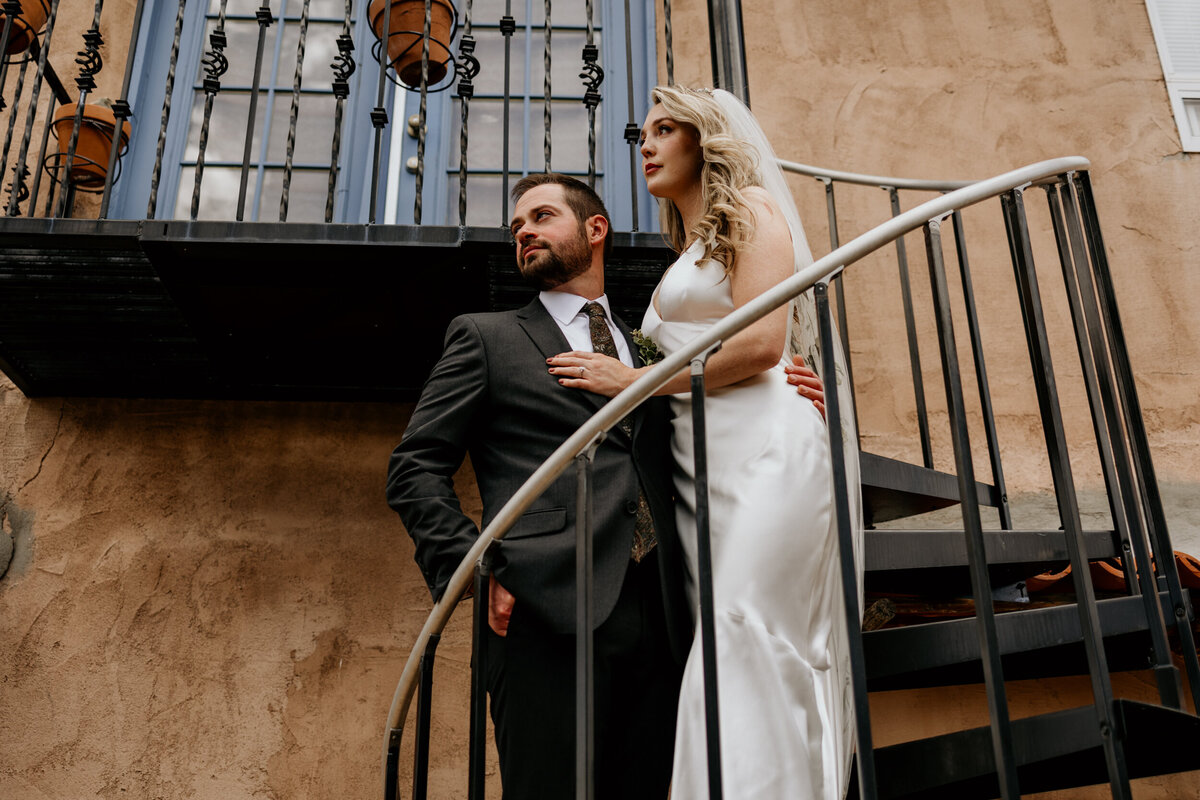 bride and groom standing on a spiral staircase together on a southwestern adobe home
