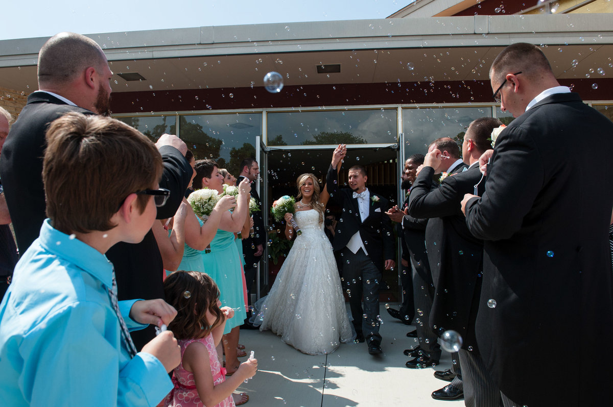 guests blow bubbles to greet couple