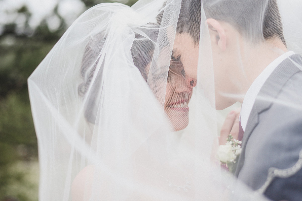bride and groom under veil together
