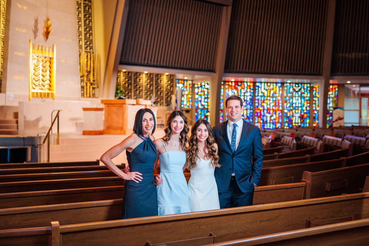 A family of 4 stands in a pew of a temple for some Bellevue Bar and Bat Mitzvah Photography
