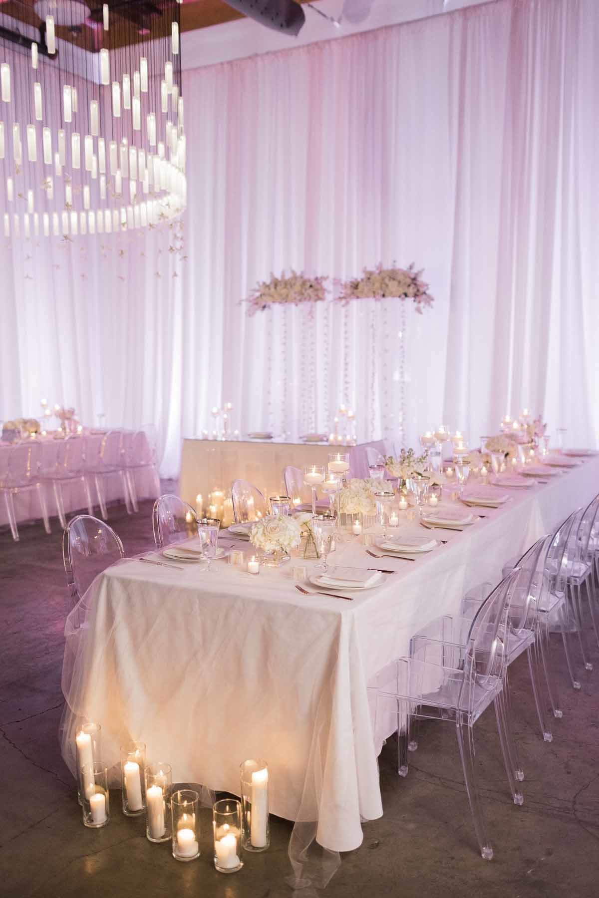 All white wedding with white draping, white linens, white flowers, and lots of candles at Canva Event Space in Seattle