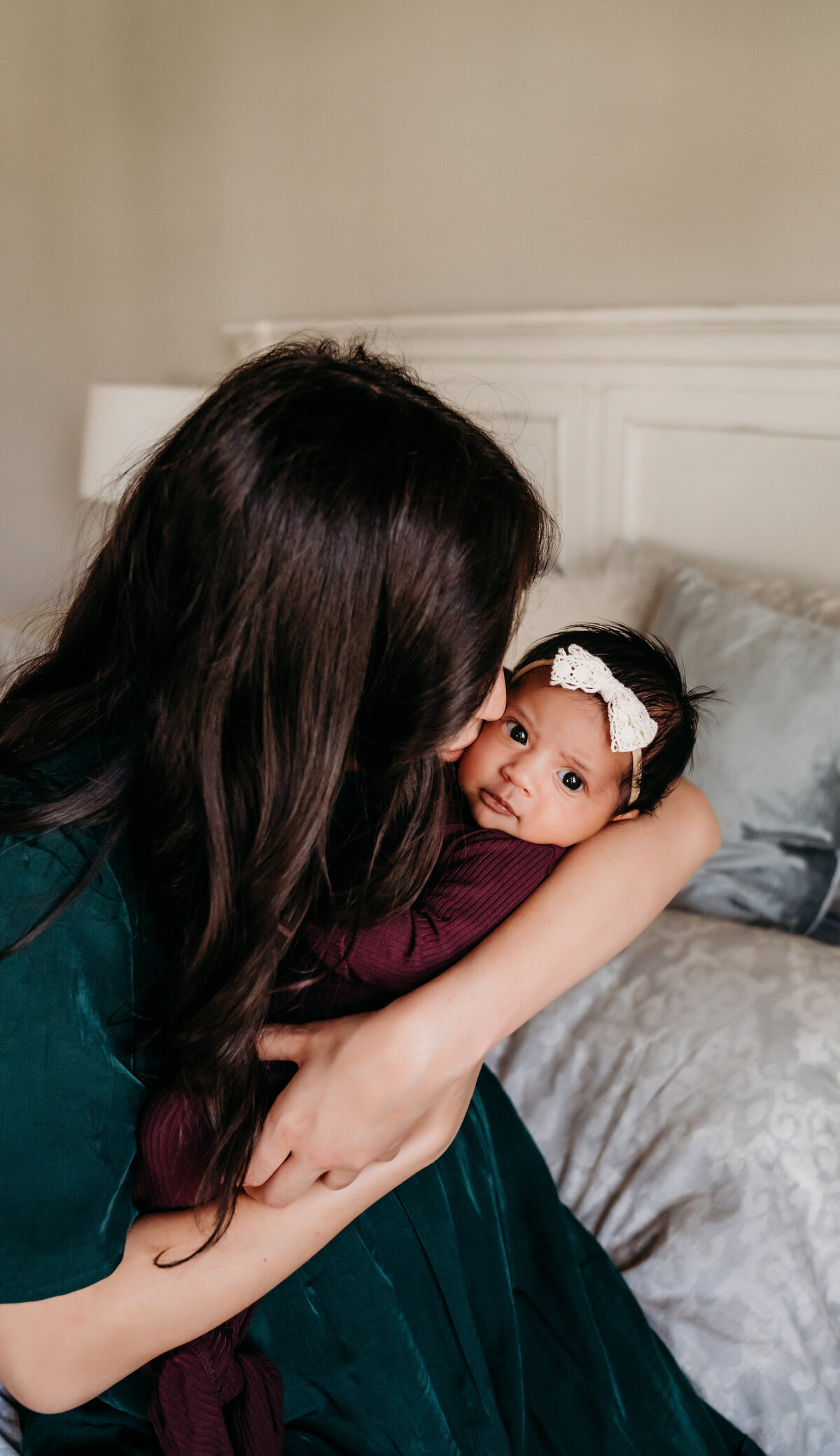 Newborn Photographer, a mother holds her baby girl in her arms at home