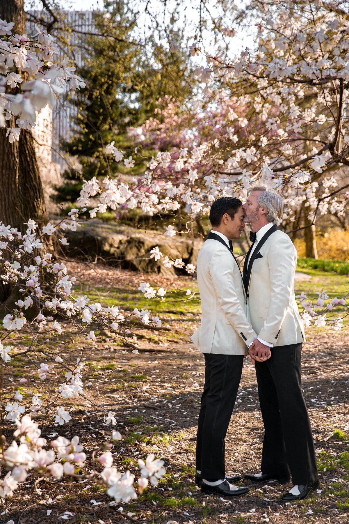 A groom kissing his husband on the forehead.