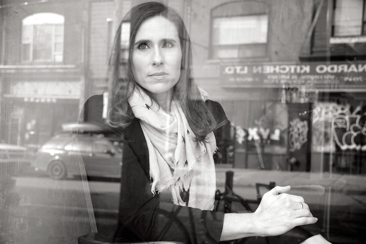 Female musician portrait Rose Cousins black and white sitting behind street reflections  on window