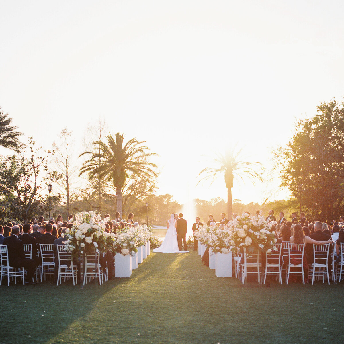 A couple exchanges vows as the sun sets behind them during their Ritz Carlton Wedding