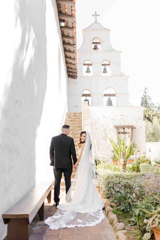 bride and groom by bell tower at the San Diego de Alcala Mission