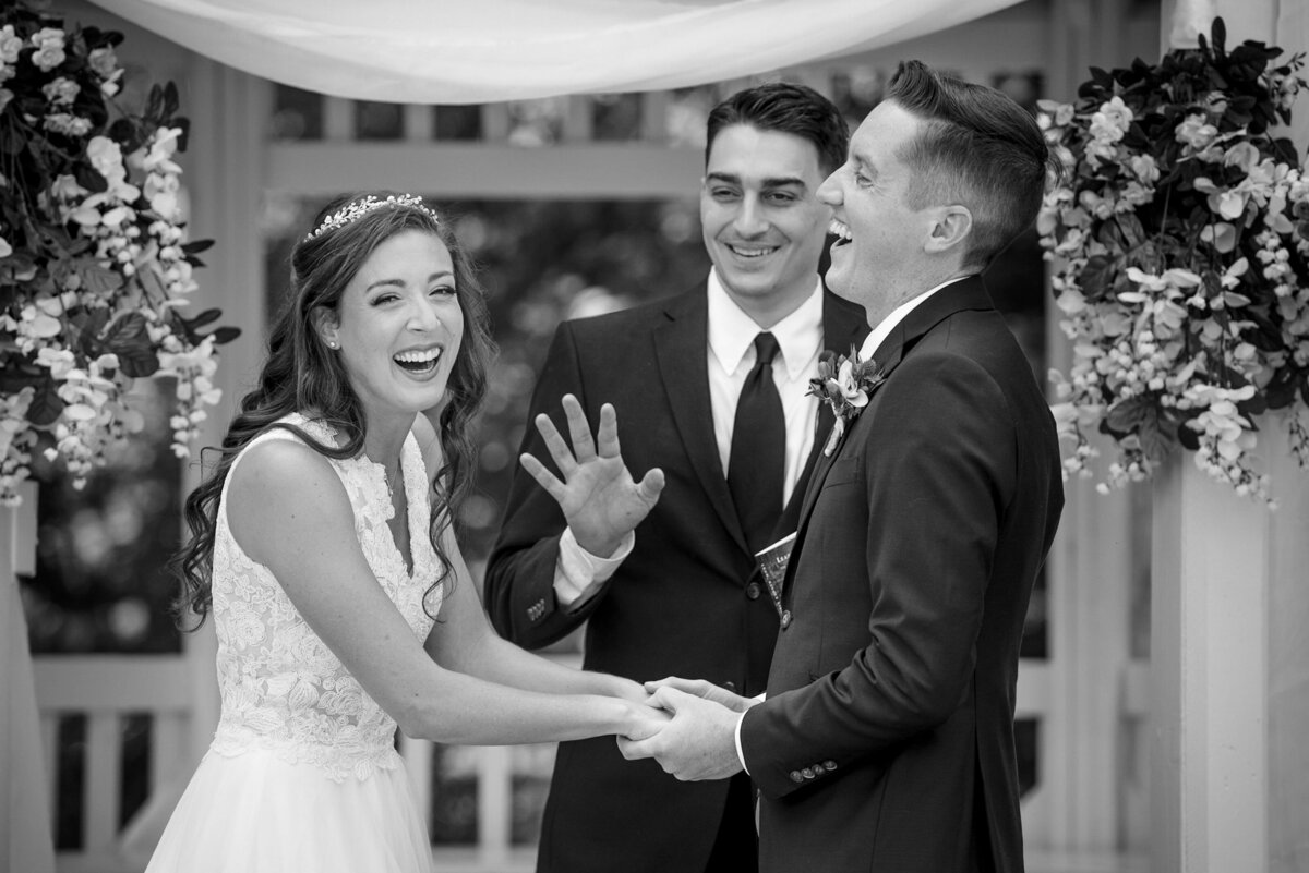Black-and-white-candid-image-of-bride-and-groom-laughing-during-wedding-ceremony-at-NorthStone-Country-Club-by-Charlotte-wedding-photographers-DeLong-Photography