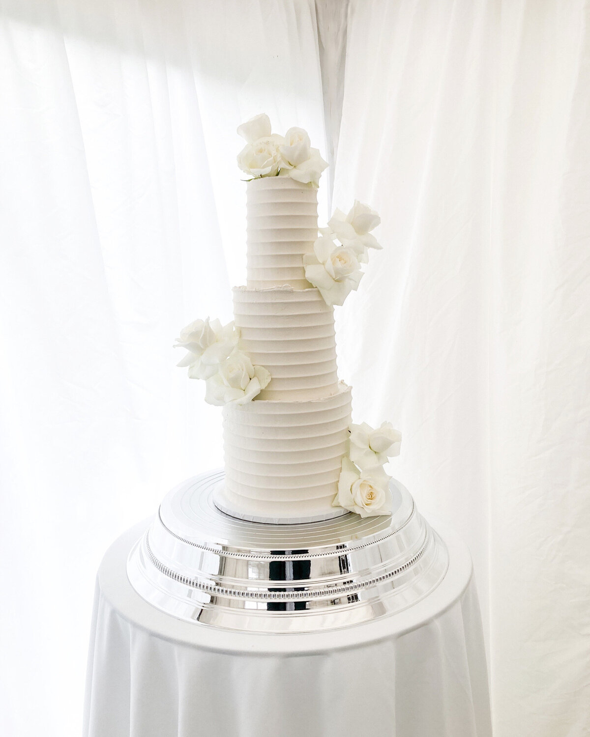 Modern white wedding cake with texture and roses