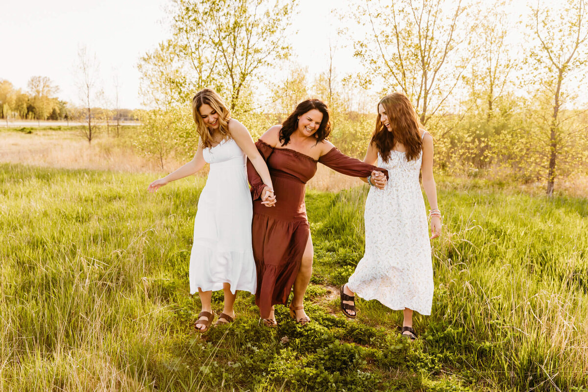 Gorgeous mother walking silly with her daughters in a field at sunset near Oshkosh