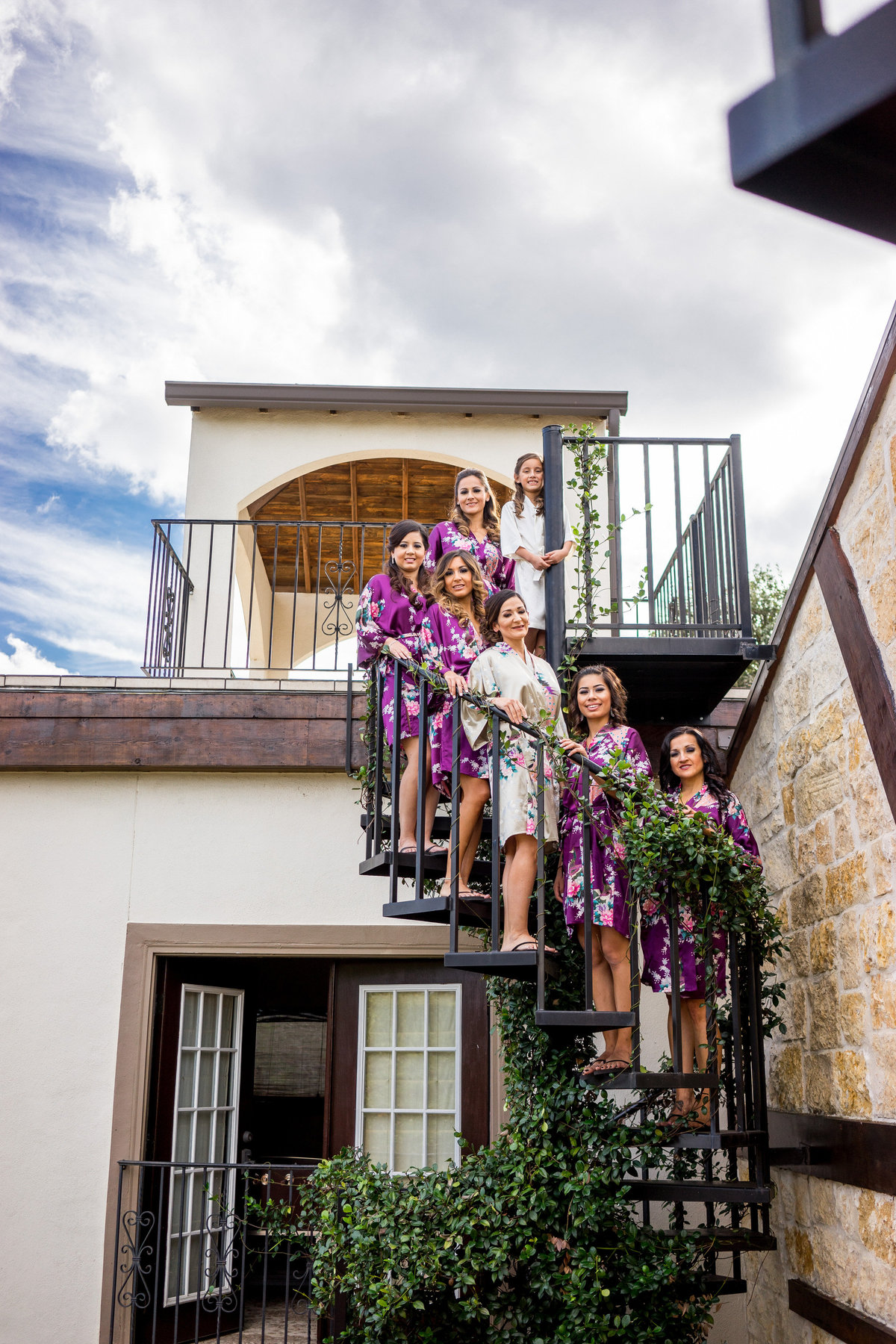 bridesmaids and bride standing on spiral stair case while getting ready for wedding ceremony at Marquardt Ranch venue
