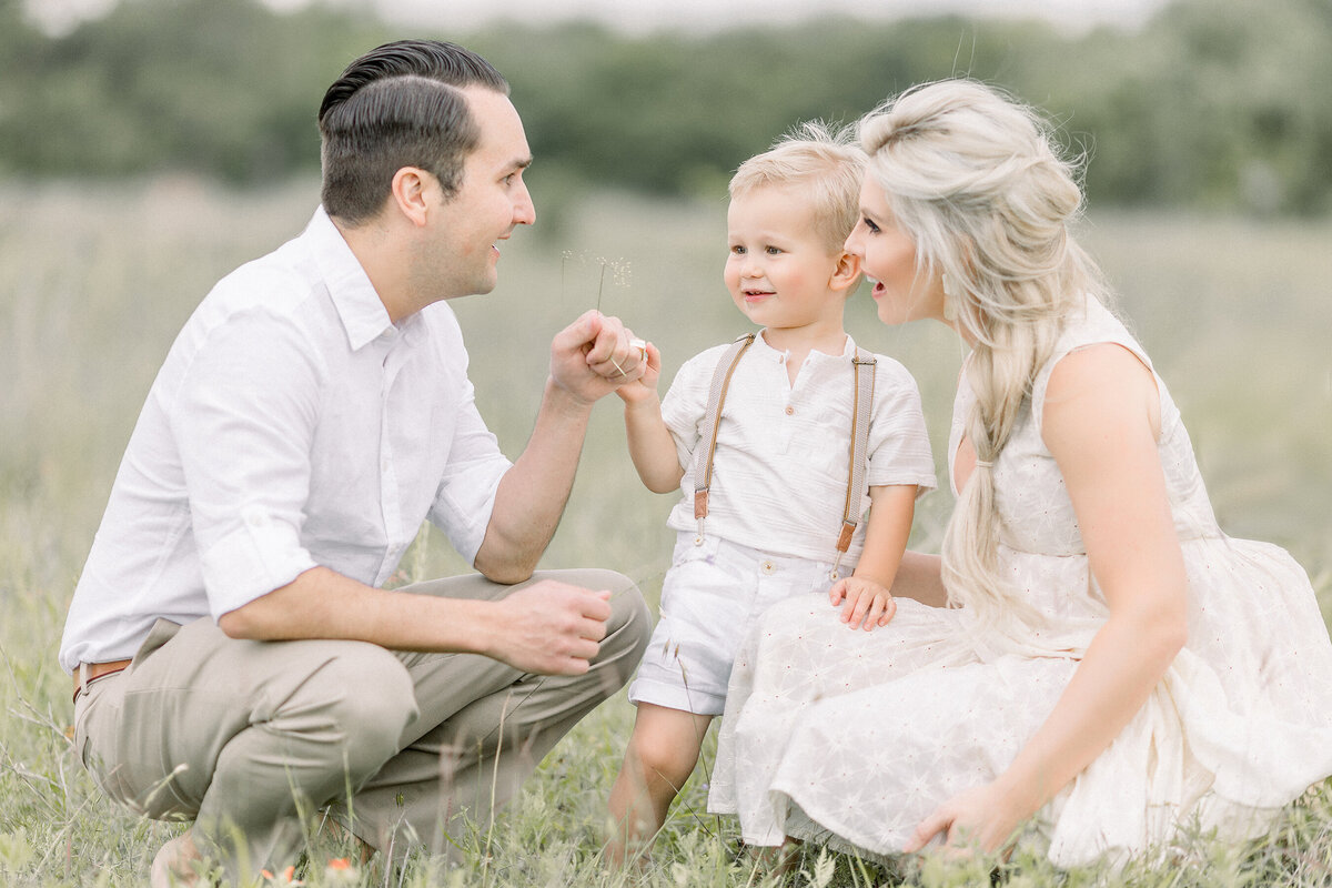 A beautiful family of 3 photo taken while they are kneeling together in a field at a local Fort Worth park taken by a family photographer in Dallas TX.