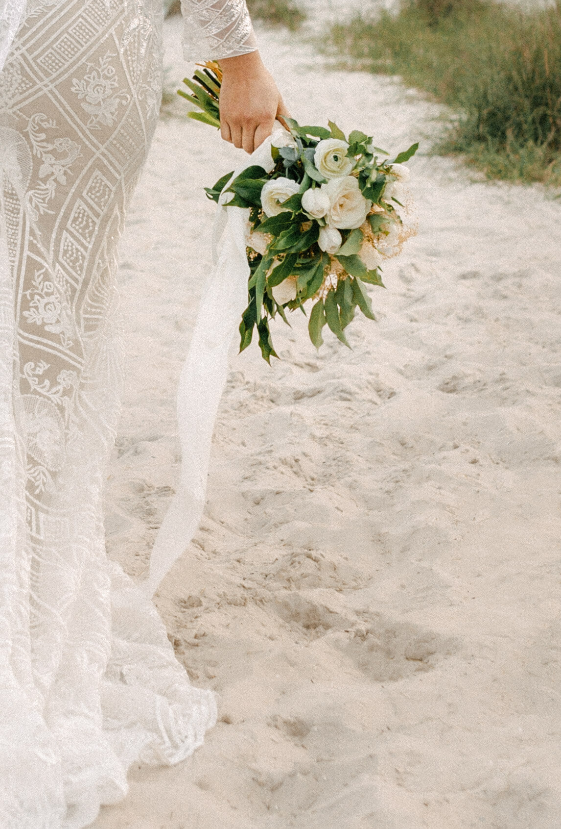 bouquet shot of asian bride in bridal dress and veil walks on beach path - taken by panama city fl photographer Brittney Stanley