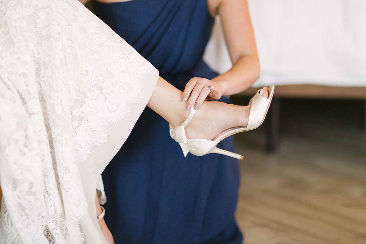 Bridesmaid helps bride put on shoes prior to wedding at Firestone Vineyard