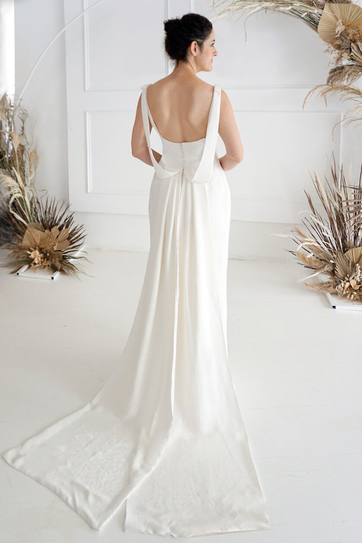 The back view of the Jealine wedding dress style features a draped back and a pair of detachable trains.