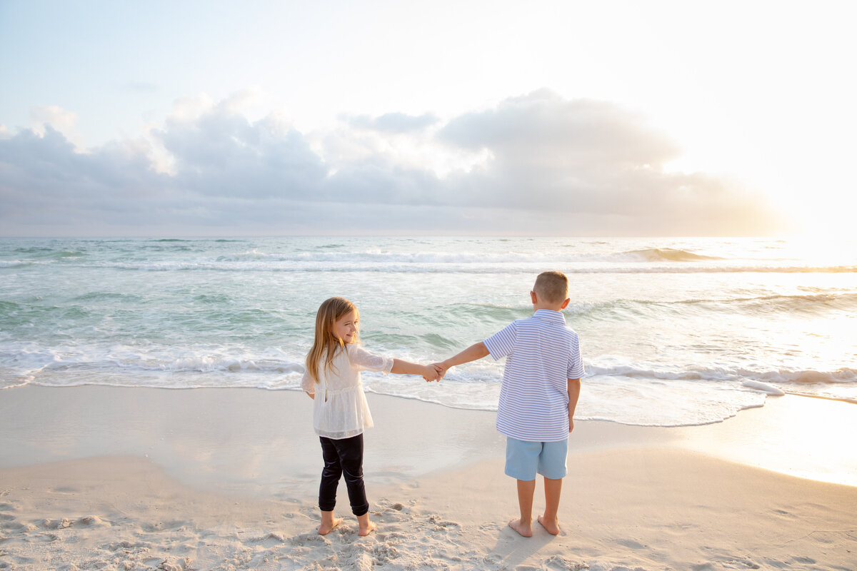 Two kids holding hands out together at the beach