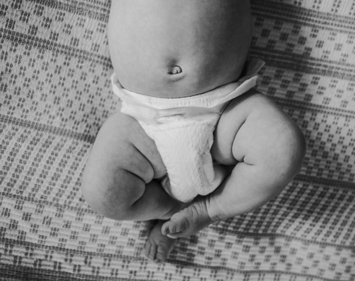 Newborn Photographer, a baby wears just a diaper and chubby legs are shown