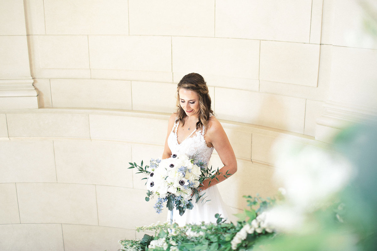 bride holding blue and white bouquet on stairway