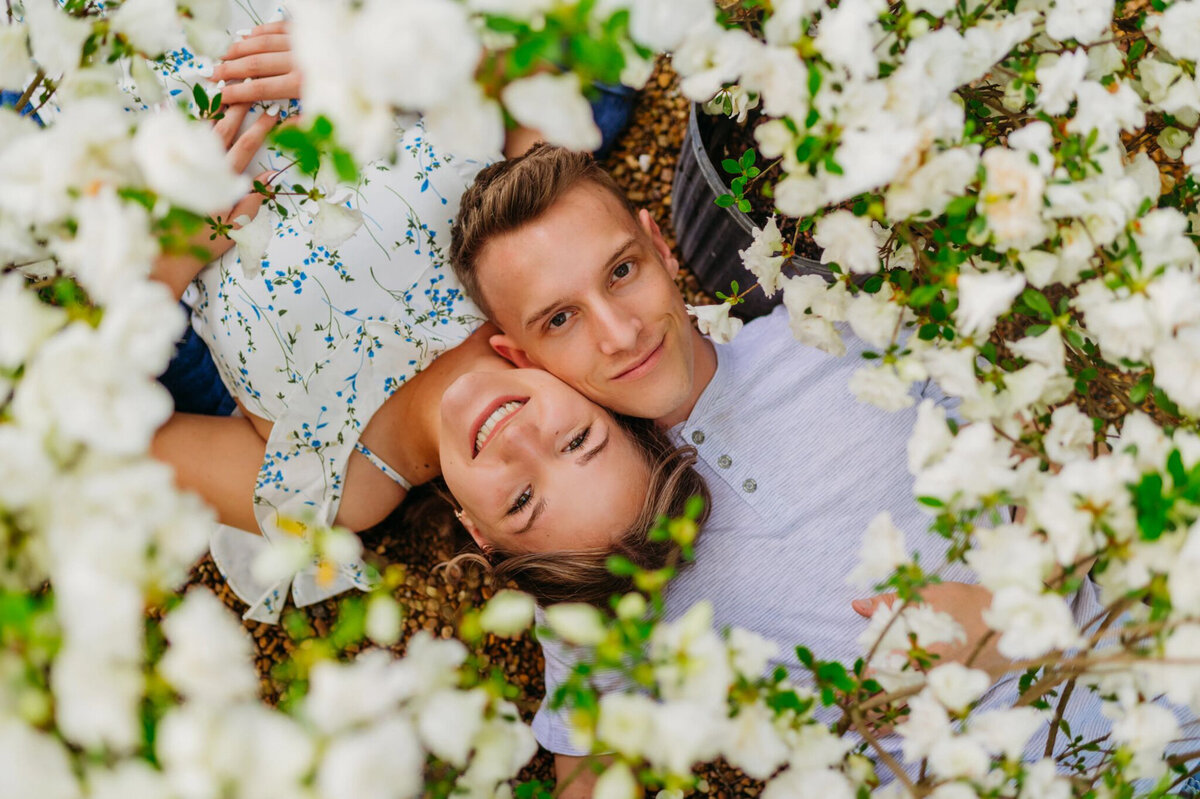photo of man and woman laying in flowers