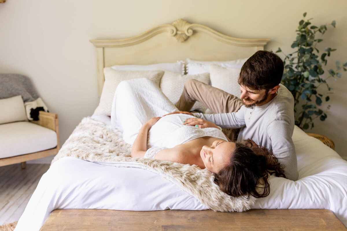 Expectant mom and dad cuddle on the bed and dream of their baby