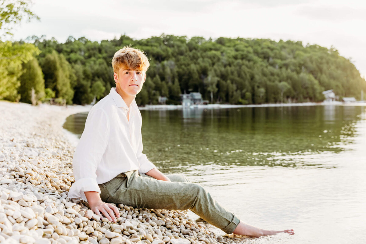 handsome teenage boy sitting while resting arms on legs by Ashley Kalbus Photography