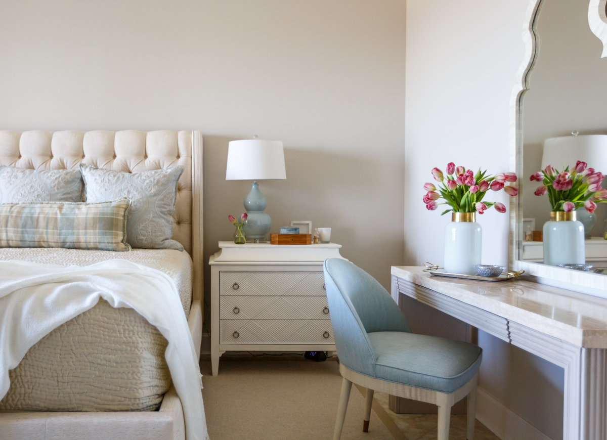 bedroom with blue chair and pink tulips on dresser