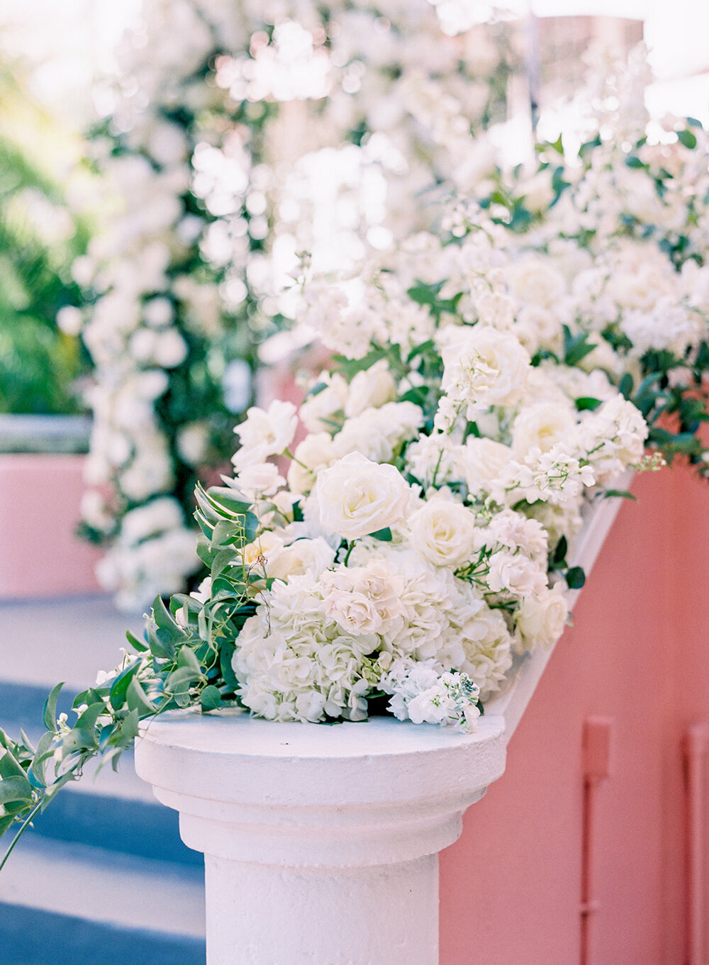 Stunning white florals cascading down the stairway banister at the Don Cesar Hotel in St. Pete Beach, FL, during a December wedding.