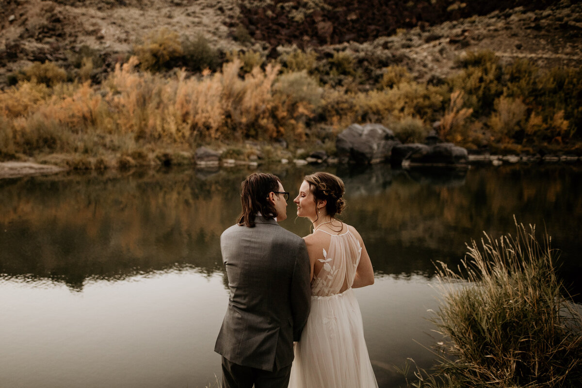 eloping couple about to kiss in front of a river