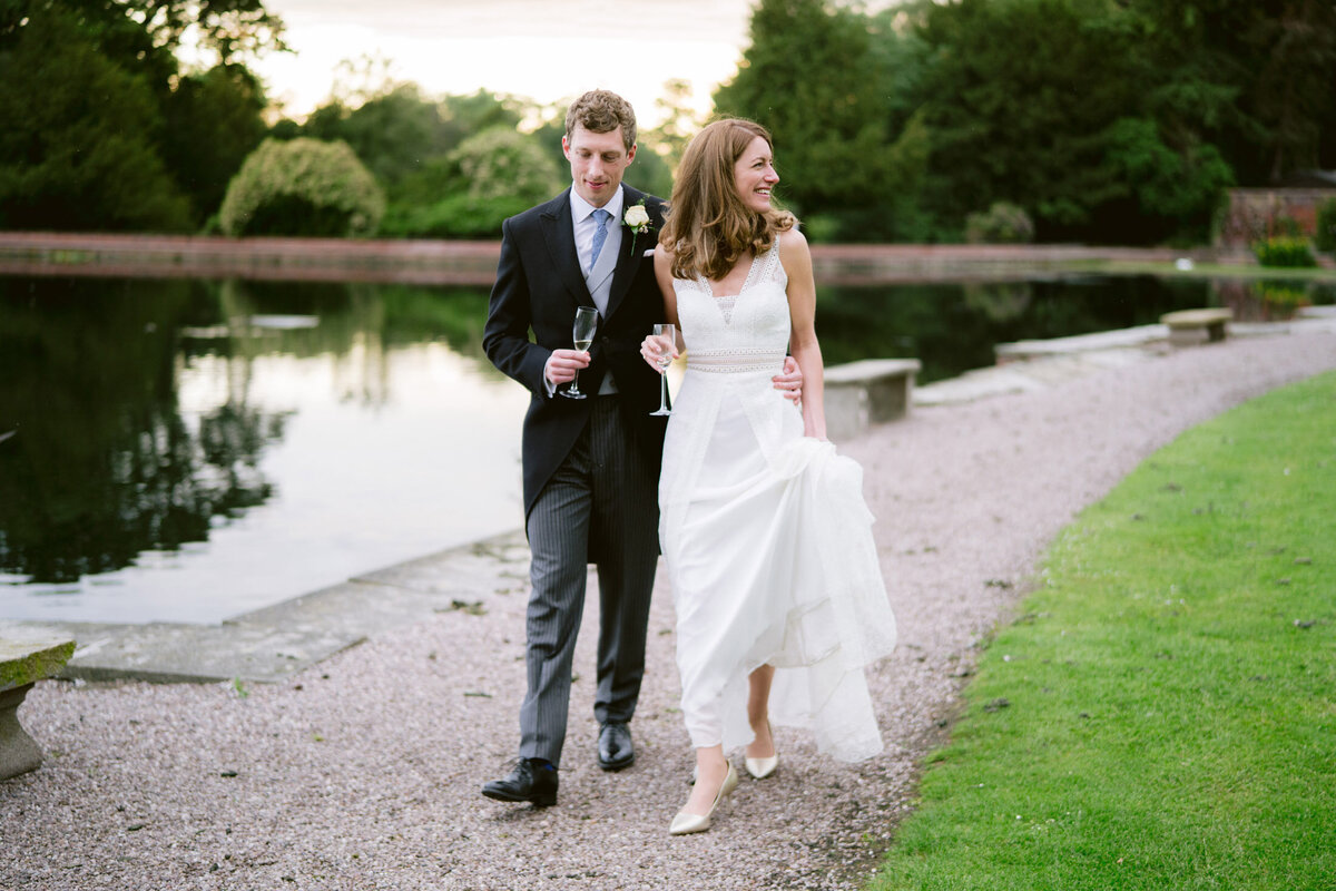wedding couple walking next to the lake at capesthorne hall in cheshire