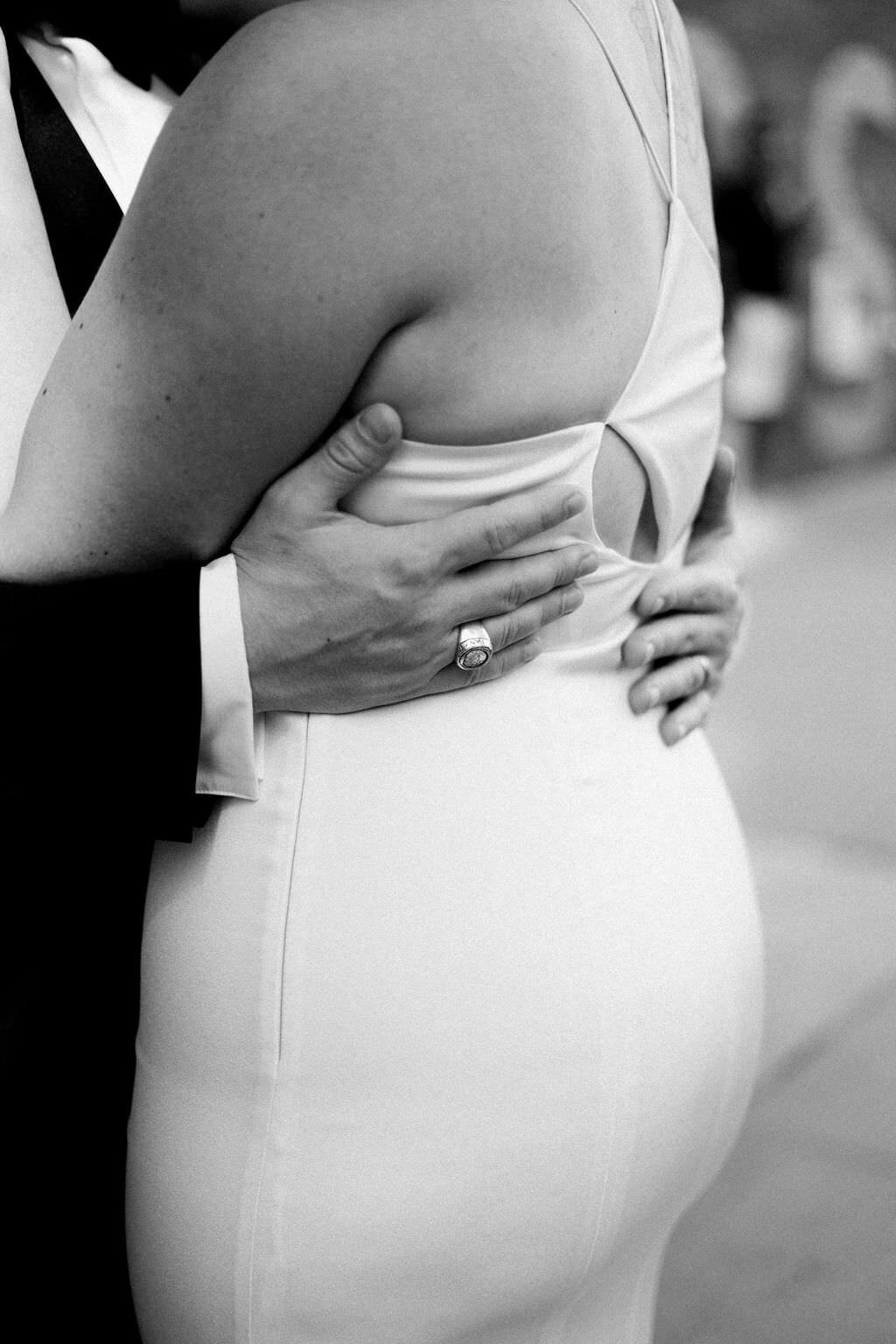 black and white photo of a grooms hands around the back of the bride