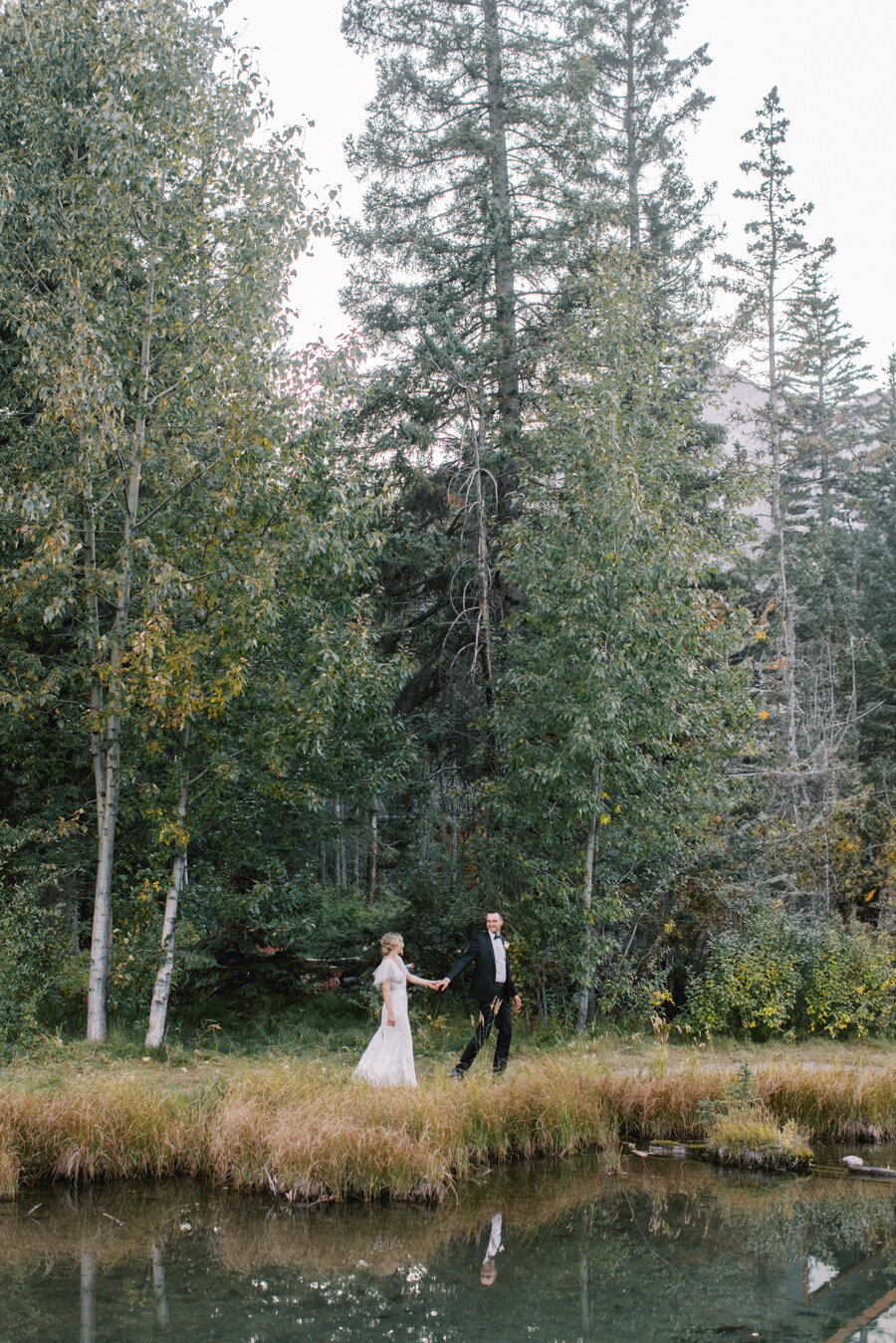 a bride and groom walking by a creek druing their Calgary wedding day