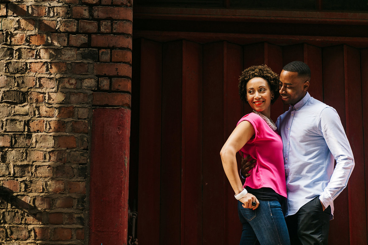 A black couple smiling and laughing whilst posed for a engagement shoot portrait