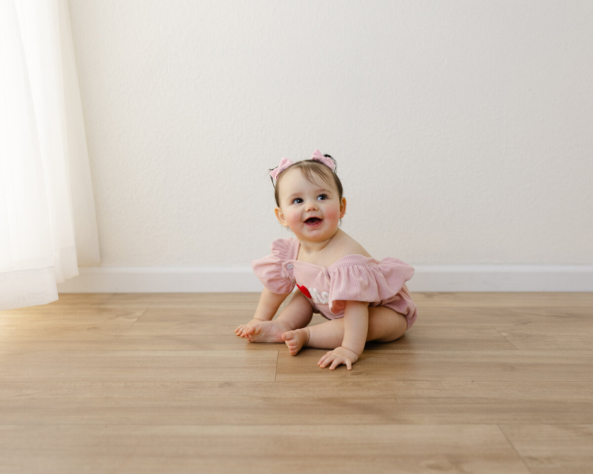 Flutter sleeves, a heart on her romper, and all the first birthday magic. Captured by Yucaipa cake smash photographer Kaitlyn Dawn Photography.