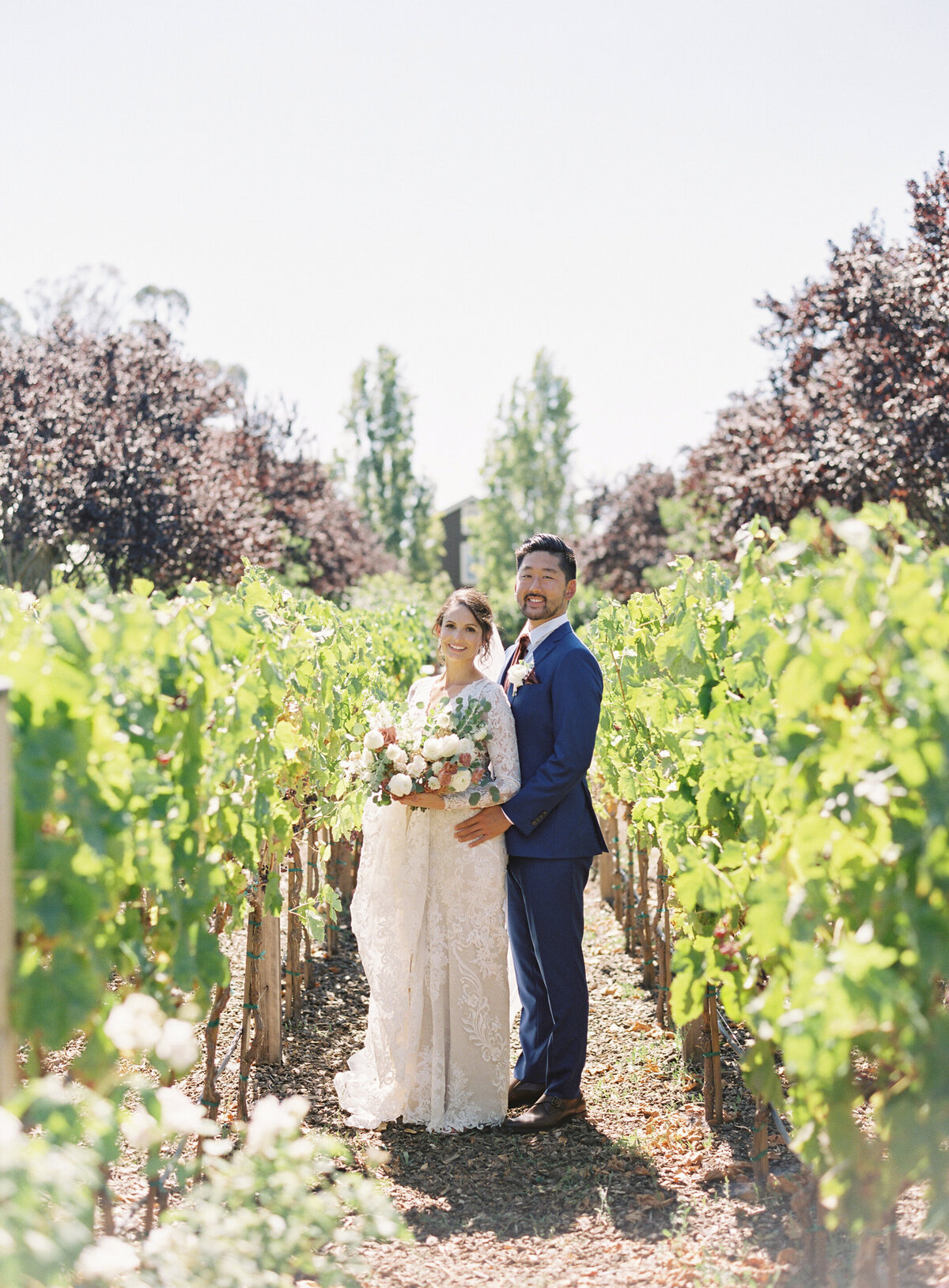 bride and groom posing in vineyard