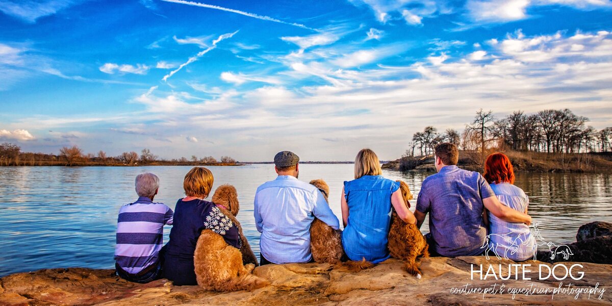 A family and their dogs sitting on the shore of Grapevine Lake, facing away from the camera.