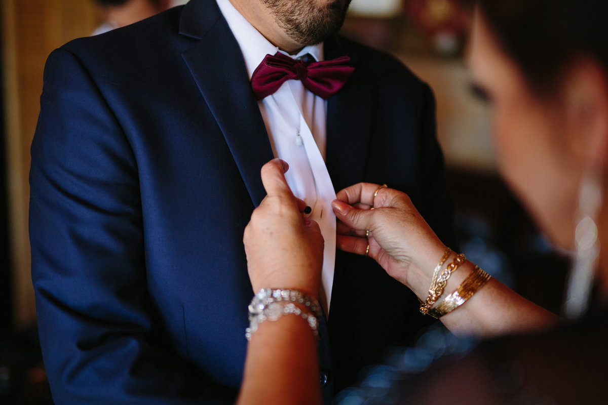mother of groom assists groom with tie before wedding ceremony in Texas Hill Country wedding