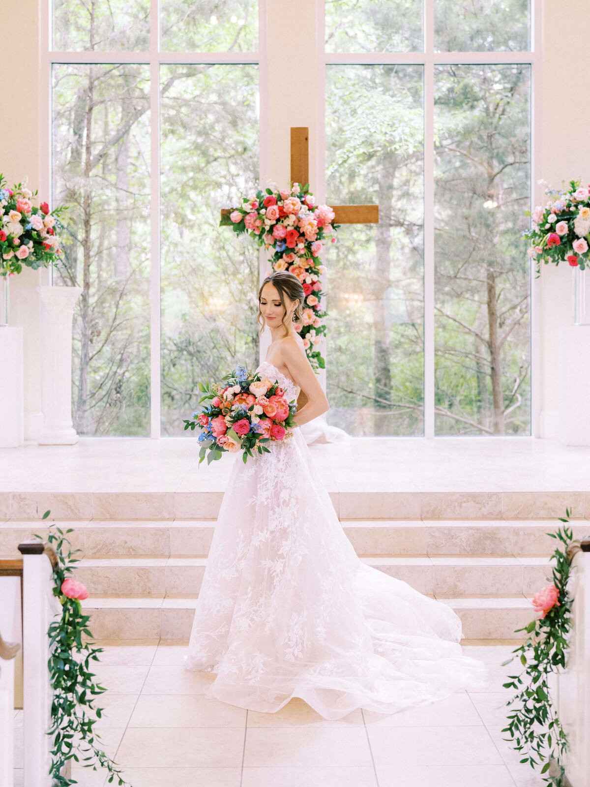 Dallas bride stands in wedding chapel surrounded by colorful vibrant florals in Monique Lhuillier dress
