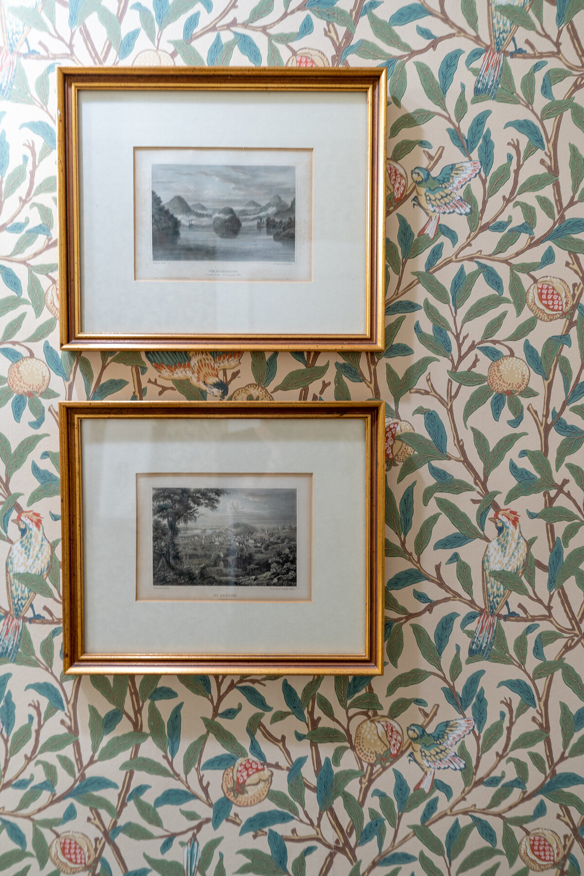 art in gold frames on a wall with pink and green botanical wallpaper