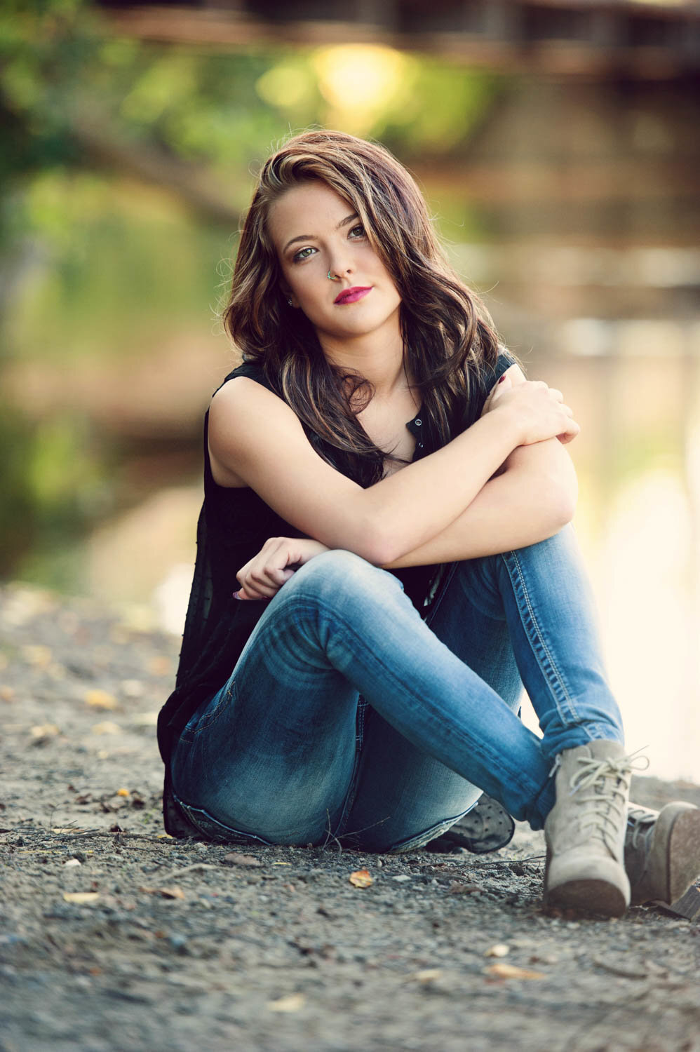 senior picture of girl sitting on river bank wearing jeans