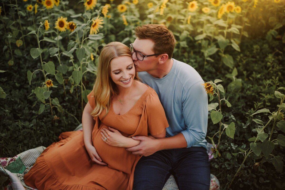 Maternity couple sitting in sunflower field