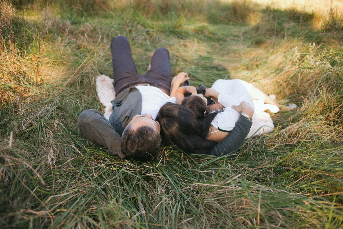 Family of three laying outdoors in long grasses in Mokena Illinois, photo by Elle Baker Photography